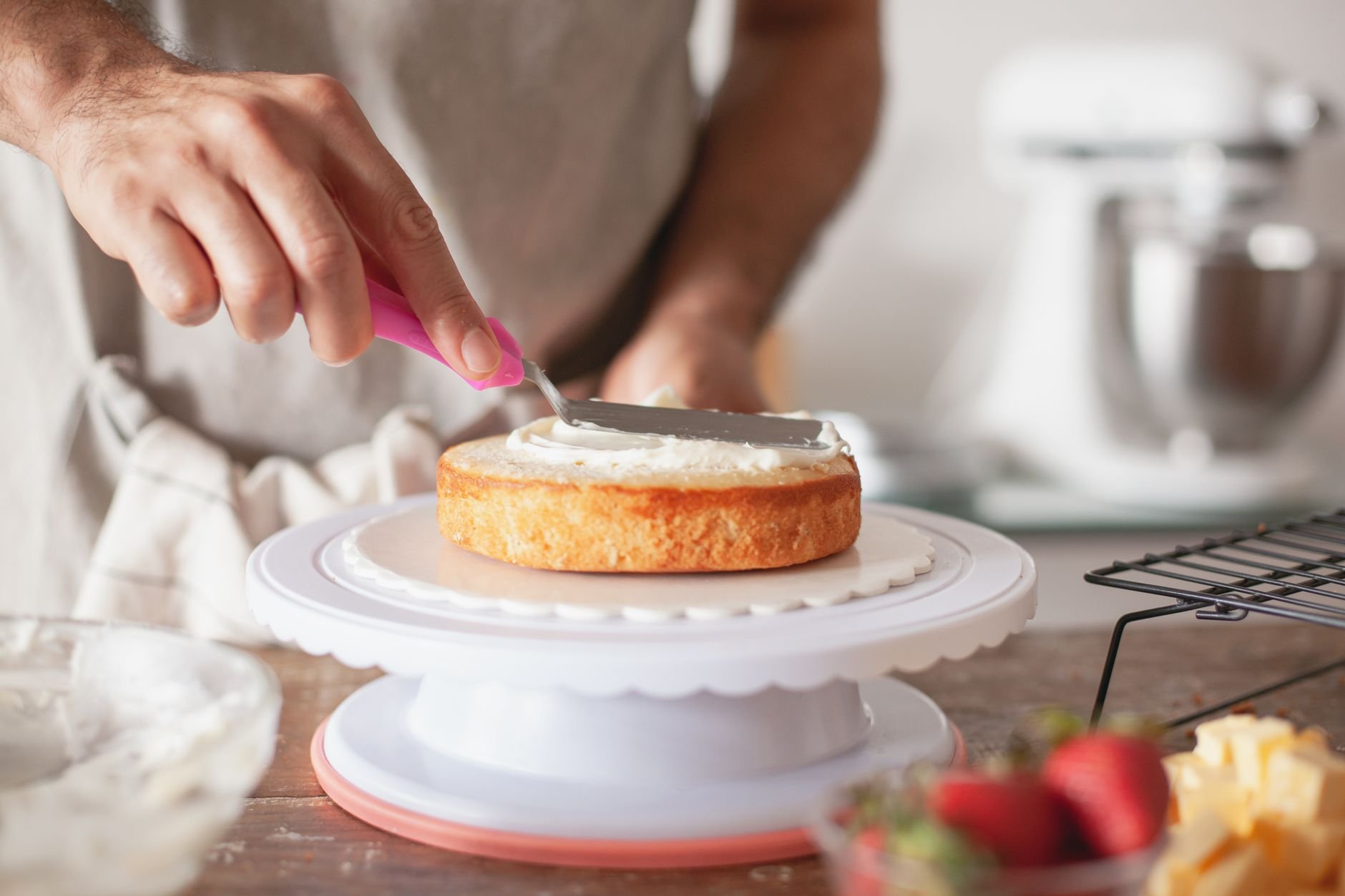 Close-up of a baker decorating a custom cake with frosting